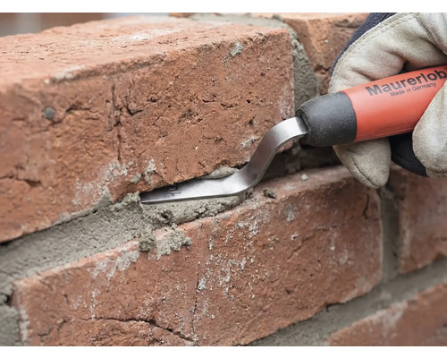Un fer à jointoyer Maurerlob est utilisé pour presser le mortier dans le joint entre deux briques rouges.