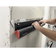 Eng Persoun benotzt eng Maurerlob Flächenspachtel fir fiichte Putz op enger Mauer glat ze sträichen.