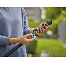 Une personne insère une bague d'étanchéité ou un filtre bleu dans une lance d'arrosage noire pour le jardin.