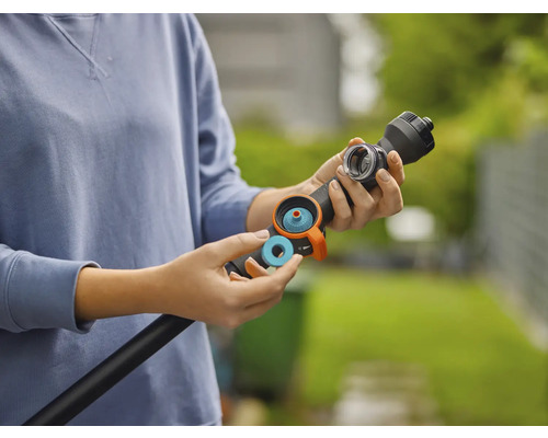 Une personne insère une bague d'étanchéité ou un filtre bleu dans une lance d'arrosage noire pour le jardin.