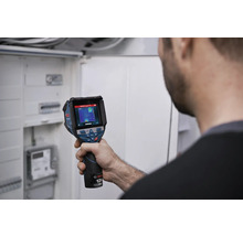 Une personne vérifie une installation électrique dans un coffret de distribution avec une caméra thermique Bosch.