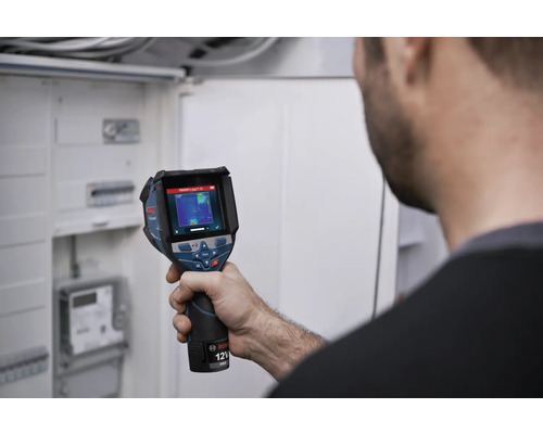 Une personne vérifie une installation électrique dans un coffret de distribution avec une caméra thermique Bosch.
