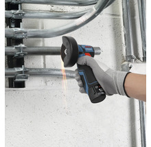 Meuleuse angulaire sans fil 12 Volt Bosch Professional coupant un tuyau métallique sur un mur avec des étincelles.