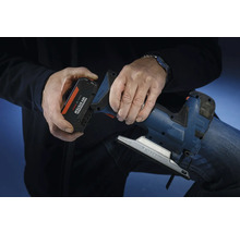 Une personne insère une batterie du système Bosch Professional 18 volts dans une scie sauteuse.