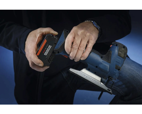 Une personne insère une batterie du système Bosch Professional 18 volts dans une scie sauteuse.