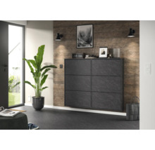 Meuble à chaussures moderne en aspect pierre avec six compartiments dans un couloir lumineux à côté d'une grande plante.