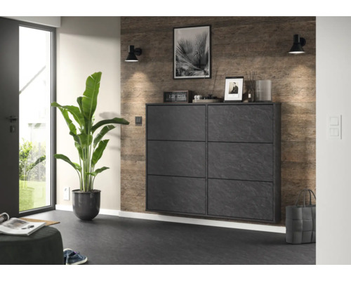 Meuble à chaussures moderne en aspect pierre avec six compartiments dans un couloir lumineux à côté d'une grande plante.