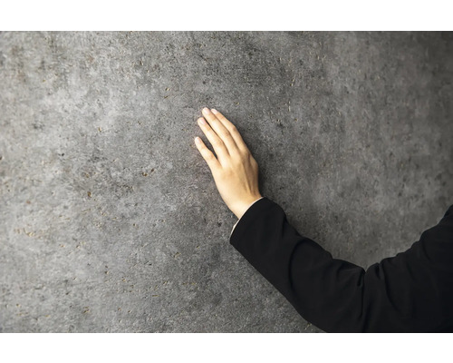 Eine Hand berührt eine strukturierte Wandverkleidung in Steinoptik.