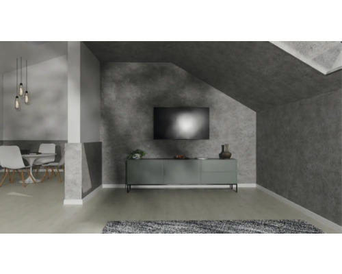 Modernes Wohnzimmer mit Wänden in Betonoptik, einem grauen Sideboard unter dem TV und einem Essbereich im Hintergrund.