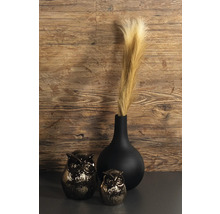 Vase noir avec de l herbe de la pampa à côté de deux figurines de hibou devant un mur en bois.
