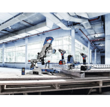 Auswahl an Bosch Professional Elektrowerkzeugen wie Kapp- und Gehrungssäge, Akkuschrauber, Stichsäge und Laser-Entfernungsmesser in einer hellen Industriehalle.