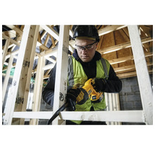 Artisan avec casque utilise une scie sabre sans fil DeWalt pour scier des poutres en bois dans une construction à ossature bois.