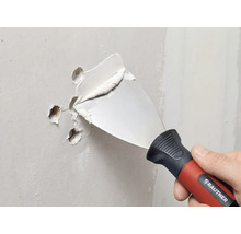 Couteau à enduire RAUTNER rebouchant des trous dans un mur avec de l'enduit.