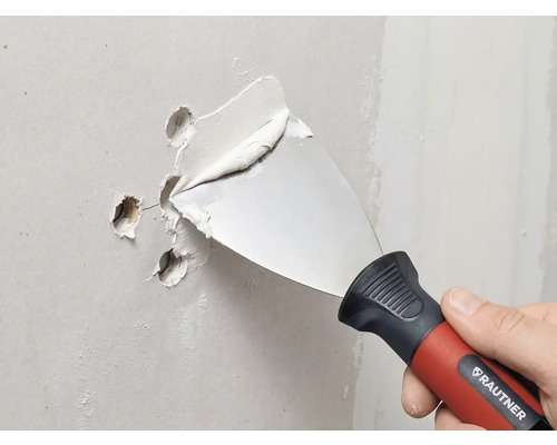 Couteau à enduire RAUTNER rebouchant des trous dans un mur avec de l'enduit.