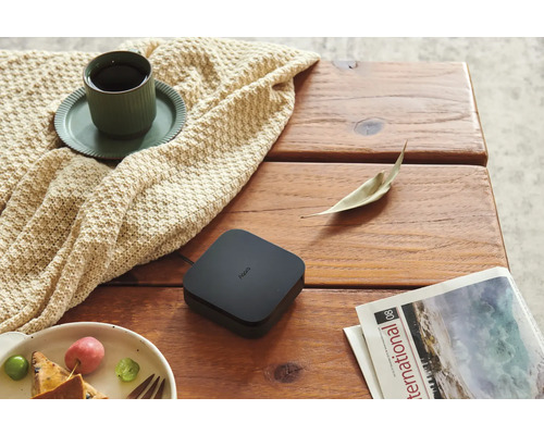 Aqara Smart Home Hub M2 sur une table en bois a cote d une tasse de cafe sur une couverture en tricot, une assiette de fruits et un magazine.