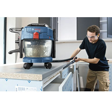 Aspirateur eau et poussière sans fil Bosch utilisé pour nettoyer un établi dans un atelier lumineux.