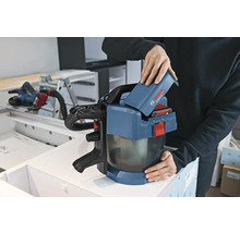 Une personne insère une batterie de 18 Volts dans un aspirateur sans fil Bosch Professional GAS 18 Volt-1 dans un atelier.