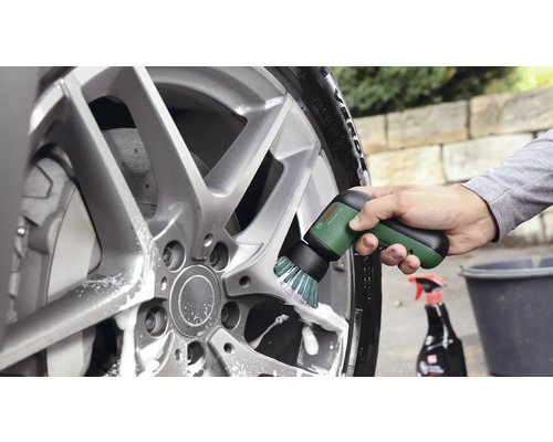 Utilisation de la brosse de nettoyage électrique Bosch UniversalBrush pour nettoyer une jante en aluminium avec de l'eau savonneuse.