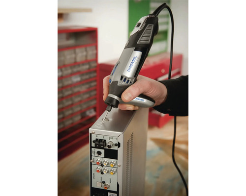 Person nutzt ein Dremel 4000 Multifunktionswerkzeug mit Präzisionshandgriff zum Gravieren eines Metallgehäuses in einer Werkstatt.