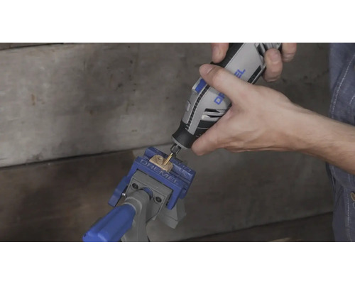 Anwendung eines Dremel Multifunktionswerkzeugs an einem Holzstück, das in einem Dremel Schraubstock fixiert ist.