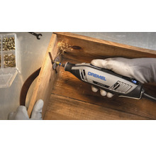 Dremel 4250 Multifunktionswerkzeug beim Schneiden einer Schraube in einer Holzkiste mit Funkenflug.