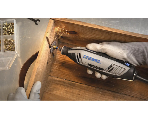 Dremel 4250 Multifunktionswerkzeug beim Schneiden einer Schraube in einer Holzkiste mit Funkenflug.