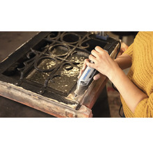 Person nutzt ein Dremel 4250 Multifunktionswerkzeug zum Bearbeiten eines Holzrahmens mit Metallgitter.