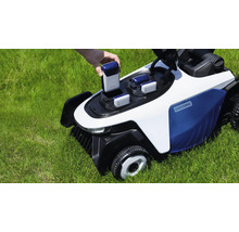 Une main insère une batterie dans une tondeuse robot Easysurge blanche et bleue sur une pelouse verte.
