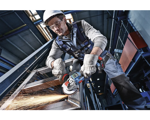Handwerker in Schutzkleidung bearbeitet eine Stahlkonstruktion mit einem Akku-Winkelschleifer unter Funkenflug.