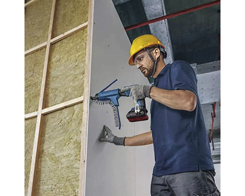Professionnel fixant une plaque de plâtre avec une visseuse à plaque de plâtre à batterie et chargeur sur une structure isolée.