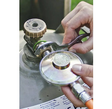 Une personne raccorde un détendeur de gaz à la valve d'une bouteille de gaz à l'aide d'une clé à gaz CFH.