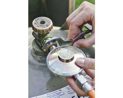 Une personne raccorde un détendeur de gaz à la valve d'une bouteille de gaz à l'aide d'une clé à gaz CFH.