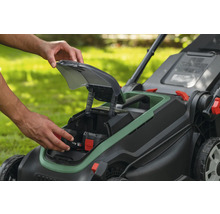 Insertion d'une batterie de 4,0 ampères-heures dans le compartiment d'une tondeuse à gazon sans fil dans un jardin.