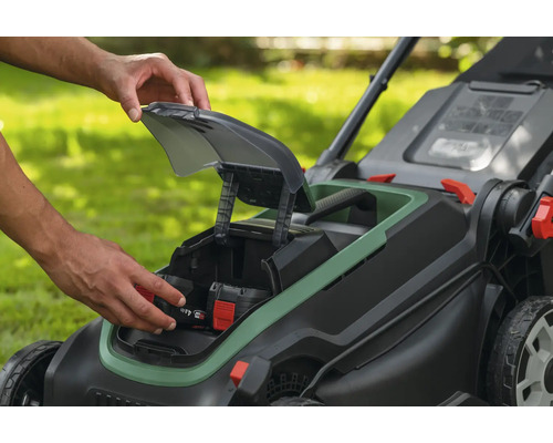 Insertion d'une batterie de 4,0 ampères-heures dans le compartiment d'une tondeuse à gazon sans fil dans un jardin.