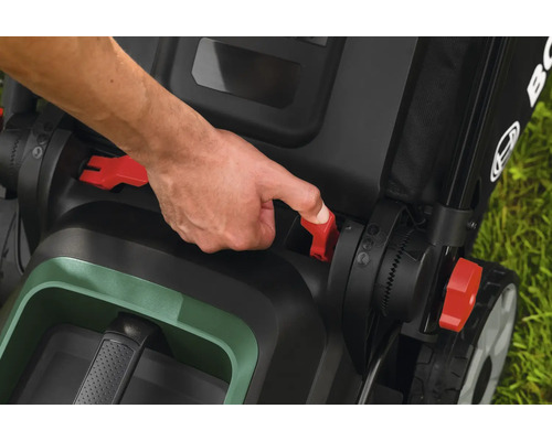 Main actionnant les leviers rouges d une tondeuse Bosch pour le réglage ou le pliage.