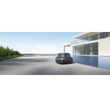Automatischer Poolroboter auf einer modernen Terrasse neben einem Pool vor einem minimalistischen Gebäude.
