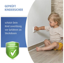 Jeune enfant assis sur le sol touchant une prise avec protection enfant. Sécurité enfant testée pour prises électriques.