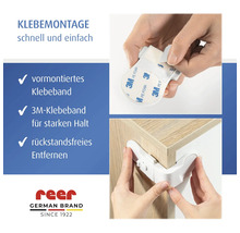 Montage einer reer Kindersicherung mit 3M-Klebeband an einer Schrankecke für starken Halt und rückstandsfreies Entfernen. reer Logo.