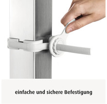 Une main serre une fixation en plastique blanc sur un poteau métallique avec une clé de montage.