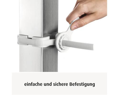 Une main serre une fixation en plastique blanc sur un poteau métallique avec une clé de montage.