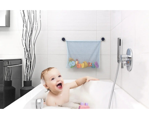 Filet de rangement bleu pour jouets de bain fixé par ventouses sur carrelage blanc au-dessus d'un enfant dans une baignoire.