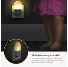 Orientierungslicht in der Steckdose erhellt dunkle Räume neben einem Kind für mehr Sicherheit bei Nacht.