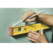 Utilisation d'un niveau à bulle Stabila pour tracer une ligne droite sur un mur avec un crayon.