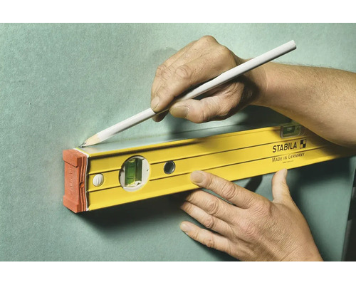 Utilisation d'un niveau à bulle Stabila pour tracer une ligne droite sur un mur avec un crayon.