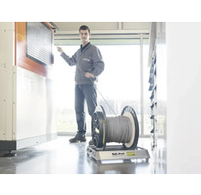 Un artisan tire un câble d'un touret sur un dérouleur Roll Profi Original dans un atelier lumineux.