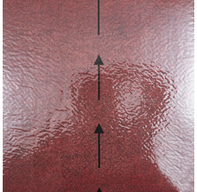 Strukturierte rote Oberfläche eines Baumaterials mit schwarzen Pfeilen zur Anzeige der Verlegerichtung.