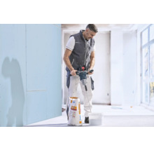 Artisan mélangeant de l'enduit dans un seau avec un malaxeur électrique à côté d'un sac de Knauf Allround.