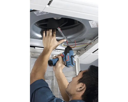 Une personne utilise une visseuse à chocs sans fil Bosch pour installer ou réparer un climatiseur de plafond.