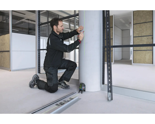 Un artisan utilise un laser à lignes croisées Bosch pour projeter une ligne laser verte verticale sur un pilier en béton pour le marquage.