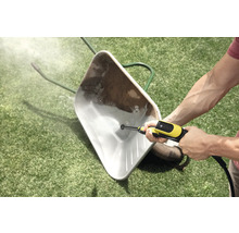 Reinigung einer verschmutzten Schubkarre auf einer Rasenfläche mit einem Hochdruckreiniger.